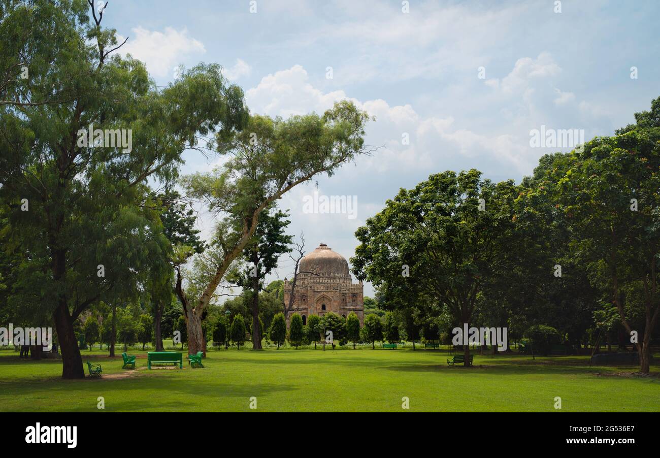 Bara Gumbad, oder große Kuppel, an einem Sommermorgen, umgeben von Bäumen und Rasenflächen unter blauem bewölktem Himmel in den Lodi-Gärten in Delhi, Uttar Pradesh, Indien Stockfoto