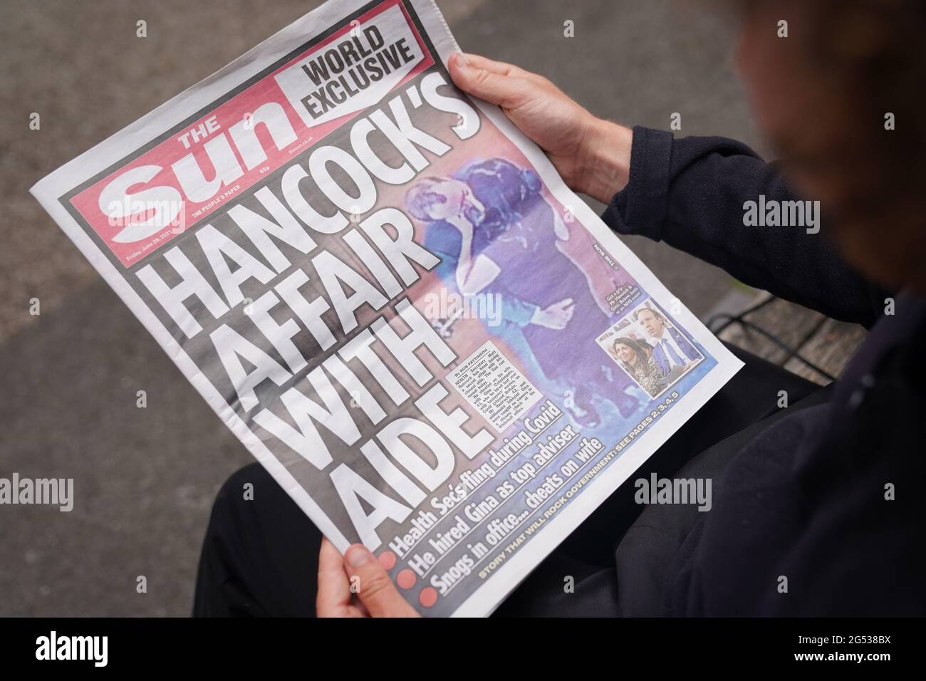 Eine Person liest eine Ausgabe der Zeitung Sun in Westminster, London, mit der Geschichte und den Bildern von Gesundheitsminister Matt Hancock, der seine Berater Gina Coladangelo küsst, die laut der Zeitung letztes Jahr von Herrn Hancock eingestellt wurde. Bilddatum: Freitag, 25. Juni 2021. Stockfoto