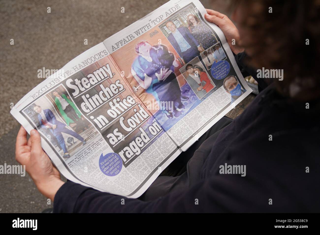 Eine Person liest eine Ausgabe der Zeitung Sun in Westminster, London, mit der Geschichte und den Bildern von Gesundheitsminister Matt Hancock, der seine Berater Gina Coladangelo küsst, die laut der Zeitung letztes Jahr von Herrn Hancock eingestellt wurde. Bilddatum: Freitag, 25. Juni 2021. Stockfoto