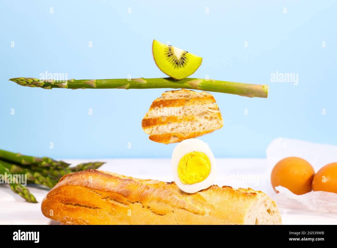 Frisches Brot, Spargel, Kiwi und Ei. Zum Frühstück gibt es Inridients. Gleichgewichtsschwimmende Lebensmittel. Balance Levitation Food. Stockfoto