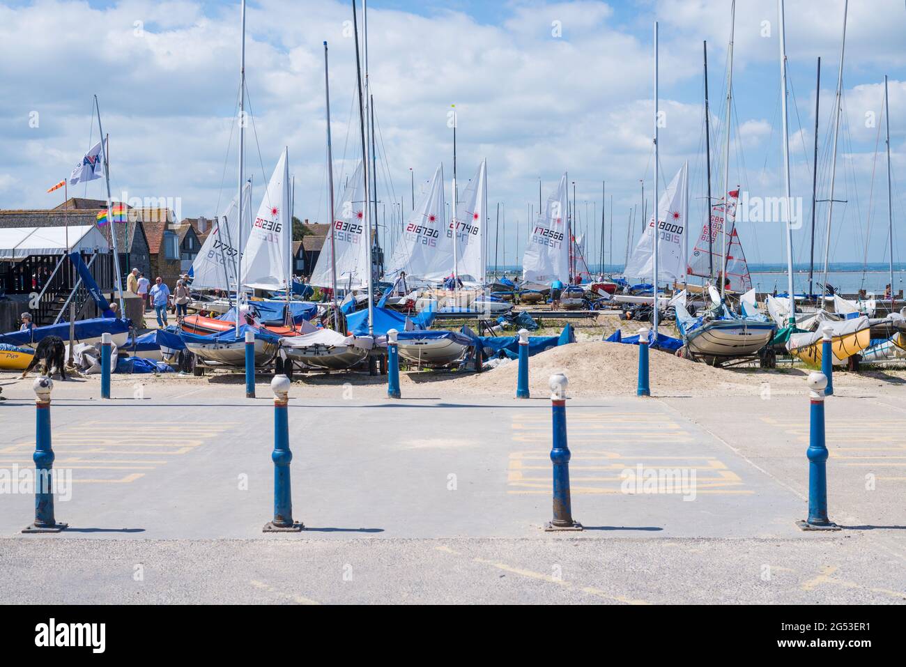 Segelboote am Strand vor dem Whitstable Yacht Club. Leute unterwegs und genießen einen warmen Sommertag am Meer. Kent, England, Großbritannien Stockfoto