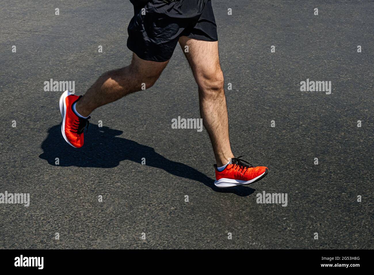 Beine Läufer Mann in leuchtend orange Schuhe laufen auf dunklem Asphalt Stockfoto
