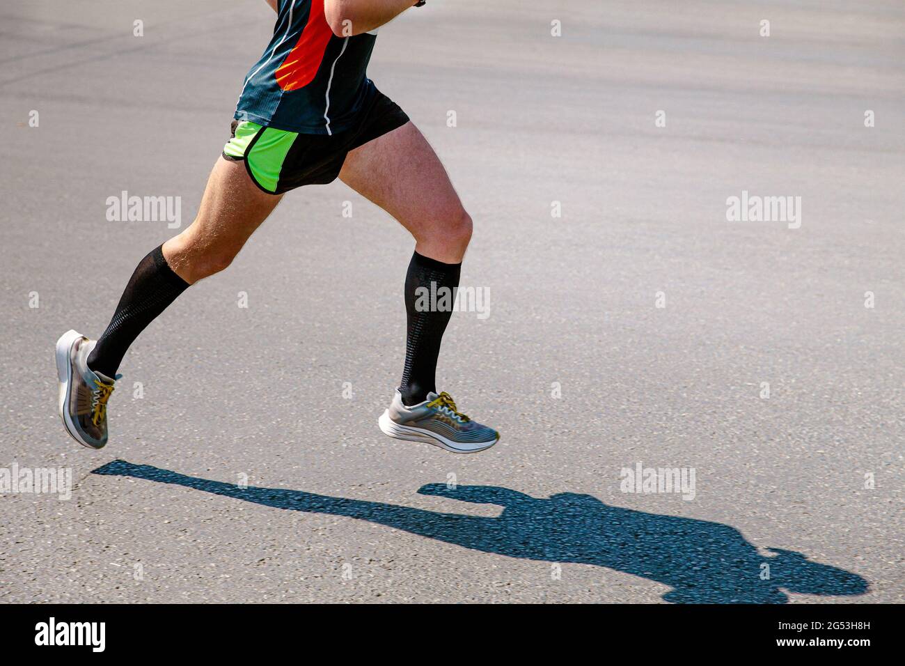 Beine männlicher Läufer in schwarzen Kompressionssocken laufen auf der Straße Stockfoto