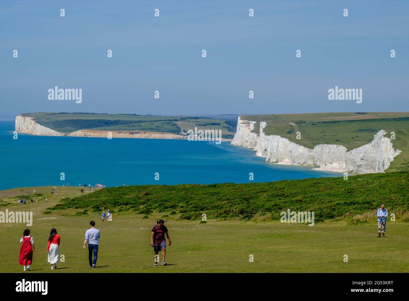 Staycation Idee. Die weißen Kalkfelsen der Seven Sisters an der Küste neben dem Ärmelkanal bei Birling Gap, wo Touristen auf dem Grasland spazieren gehen. Stockfoto