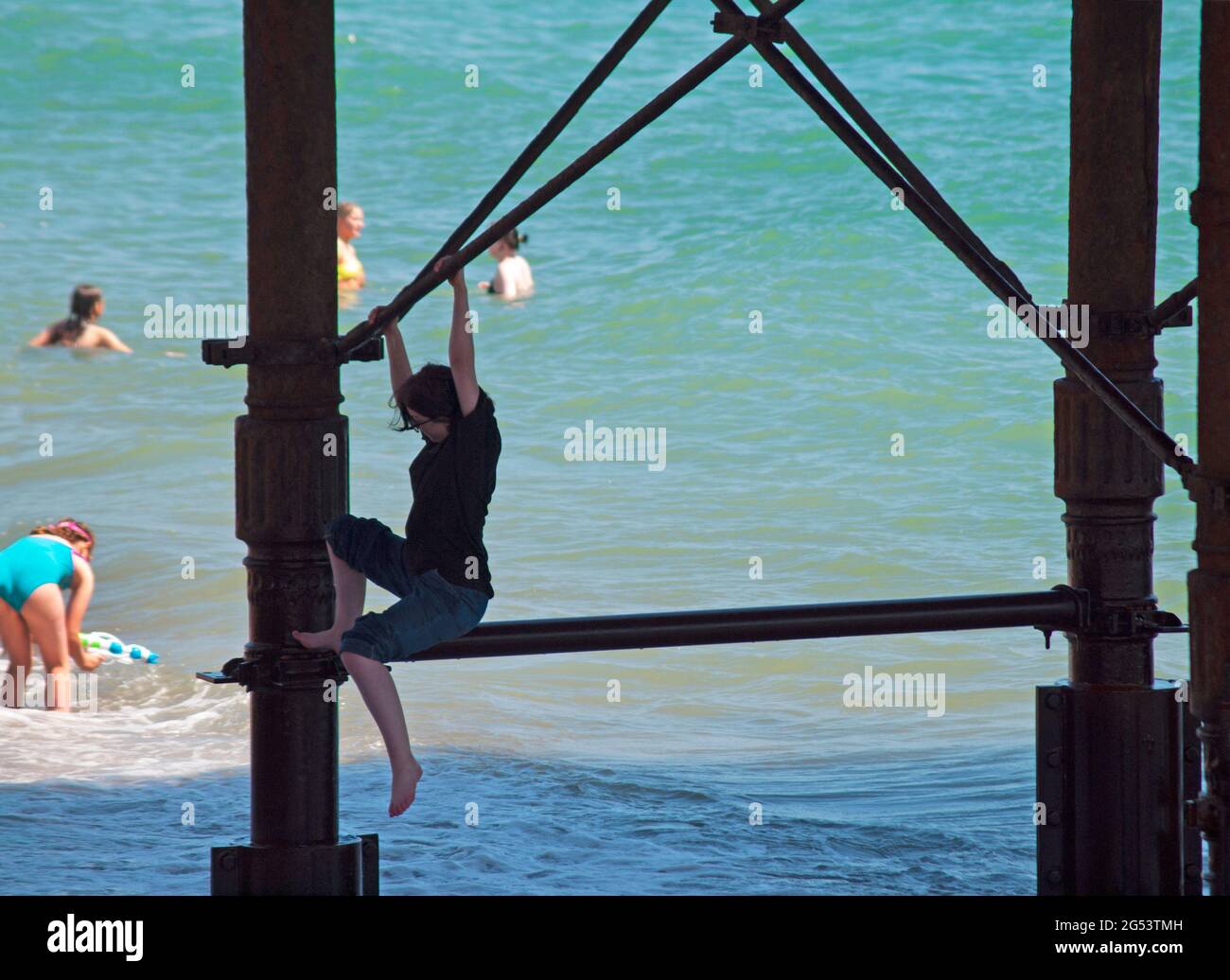 Klettern auf den eisernen Säulen, die den Brighton Palace Pier unterstützen Stockfoto