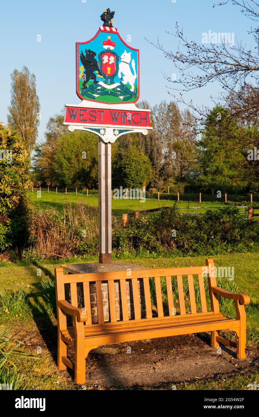 Eine Bank zum Gedenken an das silberne Jubiläum der Königin vor dem West Winch Village Schild in Norfolk. Stockfoto