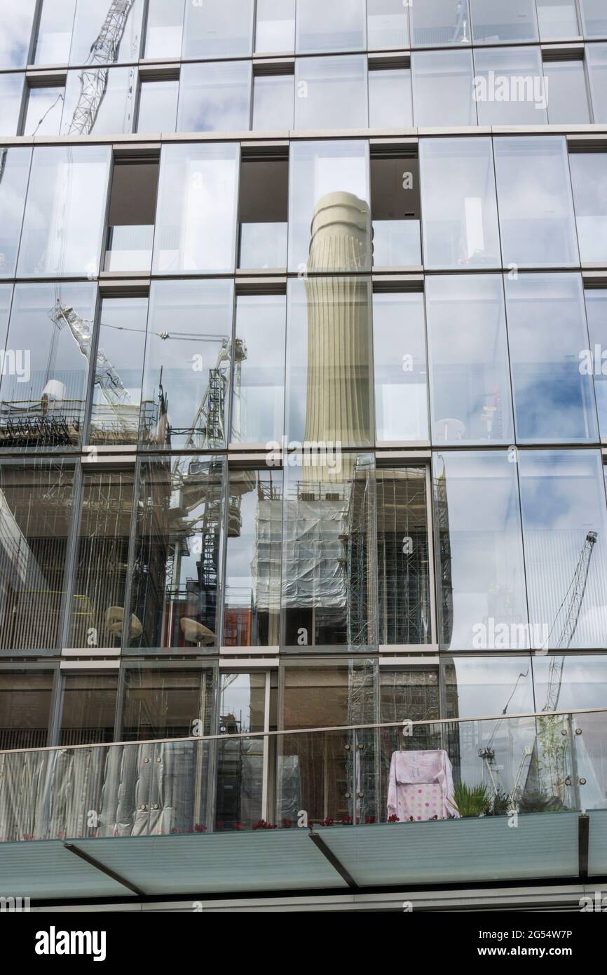 Spiegelung eines der berühmten Kamine des geschlossenen Battersea Power Kraftwerks in einer Glasfassade eines neuen Gebäudes in der Nähe. Stockfoto