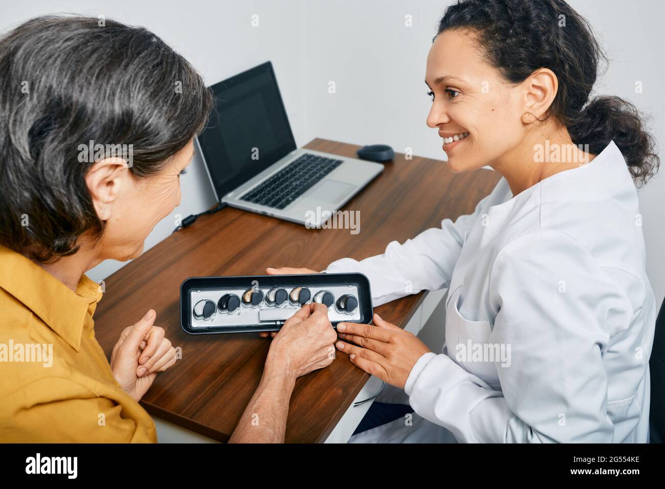 Hörgeräte. Der Audiologe wählt Hörgeräte für eine reife Patientin zur Behandlung von Hörverlust in einer medizinischen Klinik aus Stockfoto