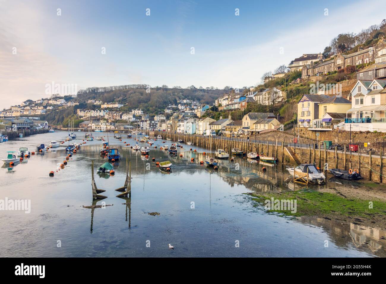 Looe Harbour in Cornwall, aufgenommen am frühen Morgen, als die Sonne ein goldenes Licht über die Szene warf. Stockfoto