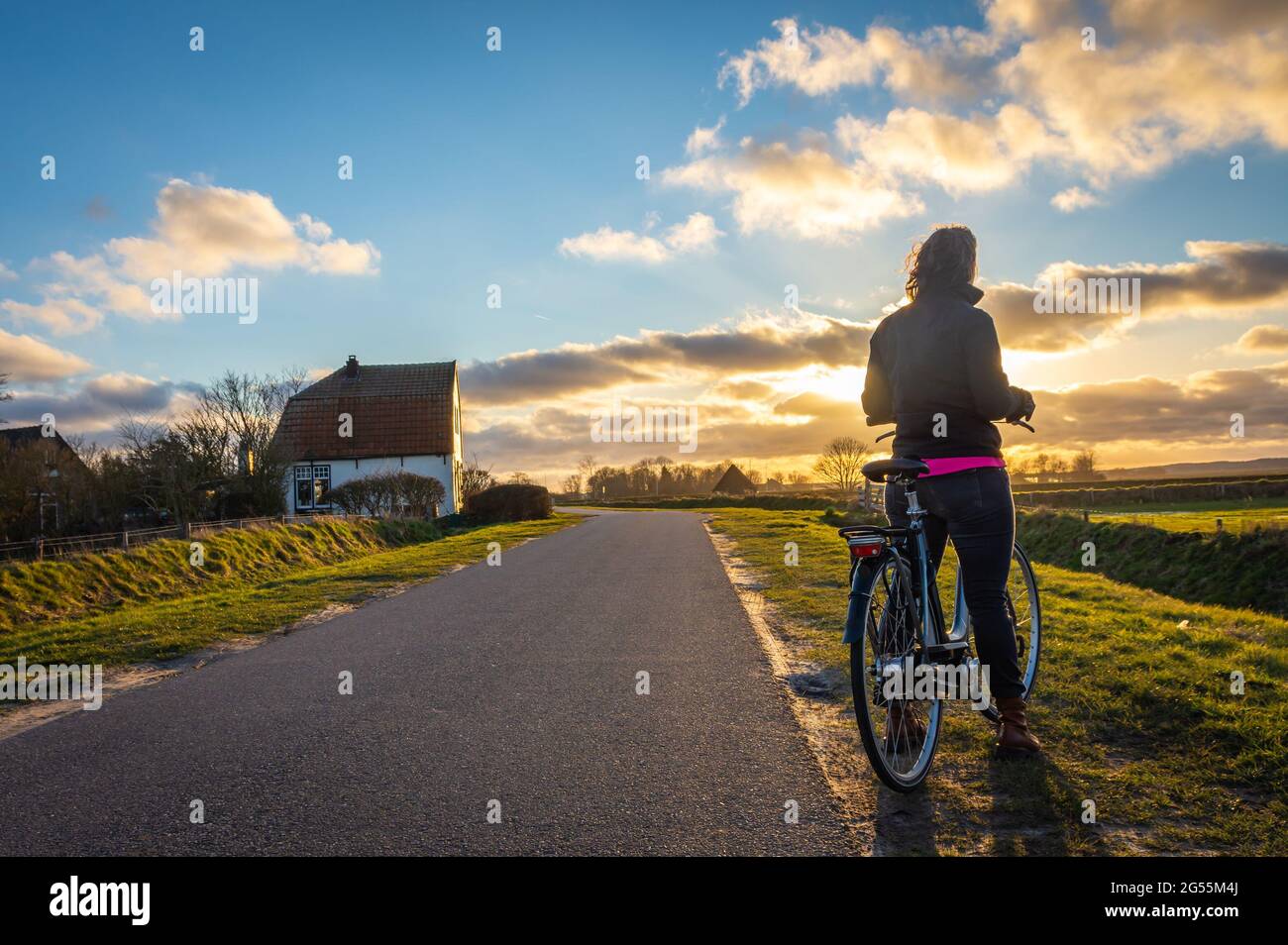Radfahrer in der niederländischen Landschaft beobachten schönen Sonnenuntergang Himmel Stockfoto