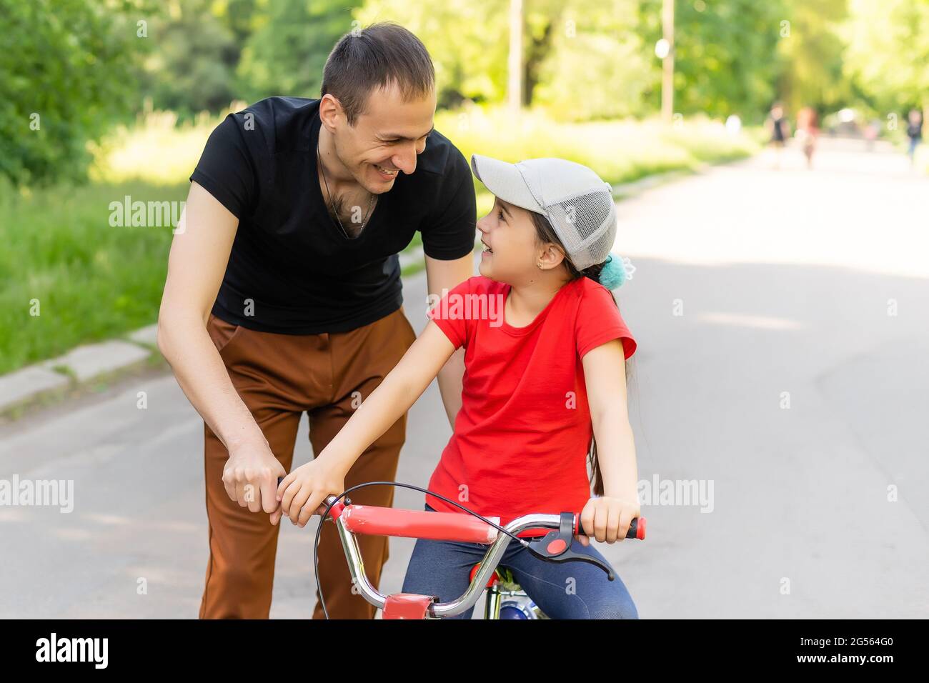 Glückliche Familie Vater lehrt Kind Tochter, ein Fahrrad im Park in der Natur zu fahren Stockfoto