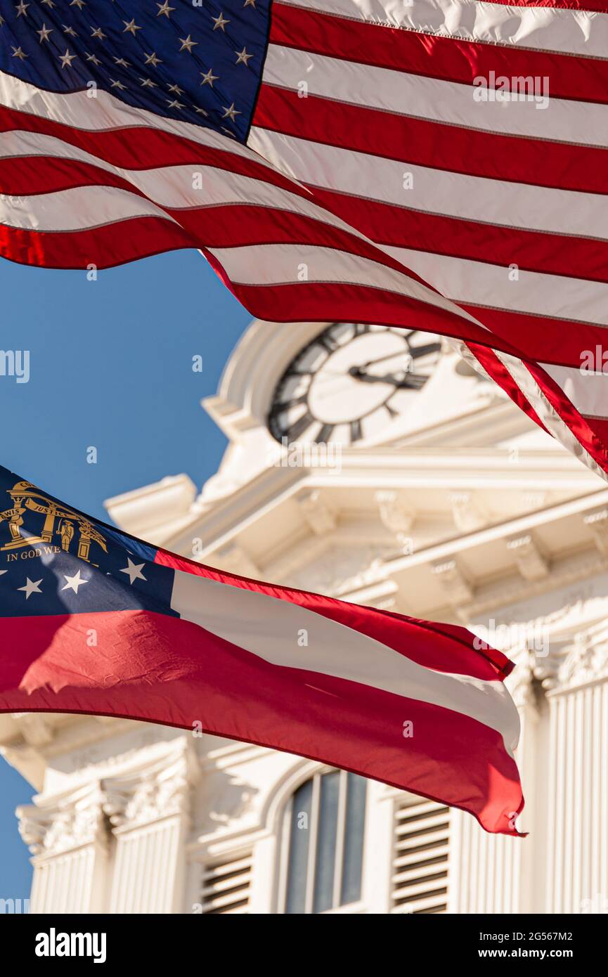 Die amerikanische Flagge und die Flagge des Staates Georgia winken vor dem historischen Gerichtsgebäude von Gwinnett auf dem Stadtplatz in Lawrenceville, Georgia. (USA) Stockfoto