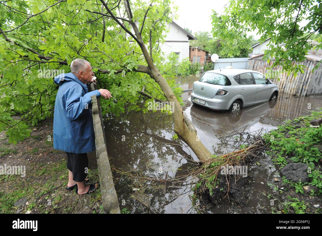 Lviv, Ukraine. Juni 2021. Ein Mann schaut auf einen umgestürzten Baum und überfluteten Wagen.nach mehreren Tagen Hitze in Lemberg kam es zu einem Regenguss und einem Gewitter mit Hagel, bei dem Bäume gefallen waren, mehrere Straßen ohne Licht und Elektrofahrzeuge angehalten wurden. Kredit: SOPA Images Limited/Alamy Live Nachrichten Stockfoto