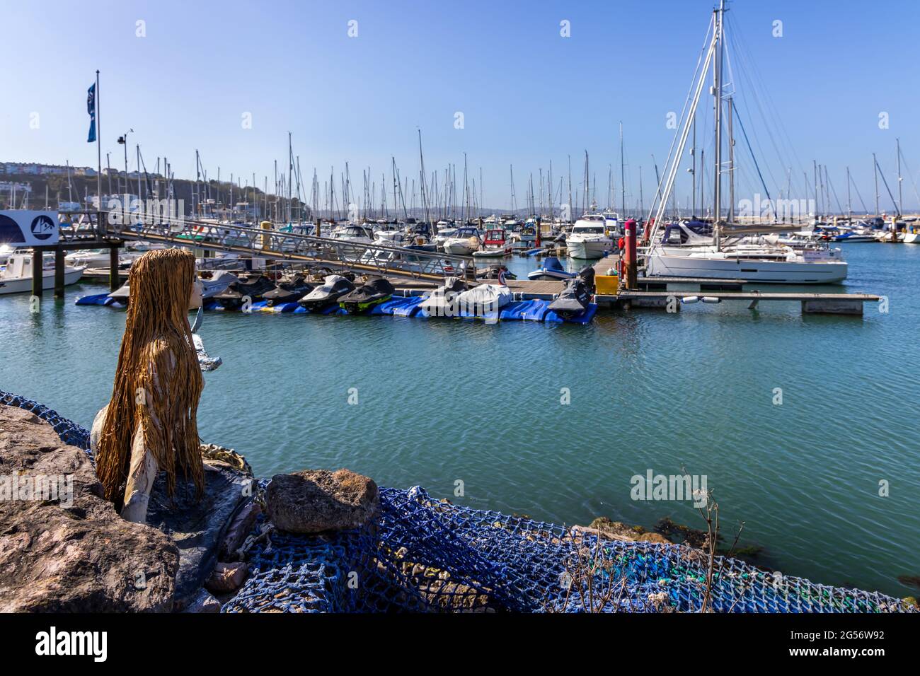 Diese wunderbare Meerjungfrau-Statue hält ein wachsames Auge über die Boote und Yachten in der Brixham Marina in South Devon. Stockfoto
