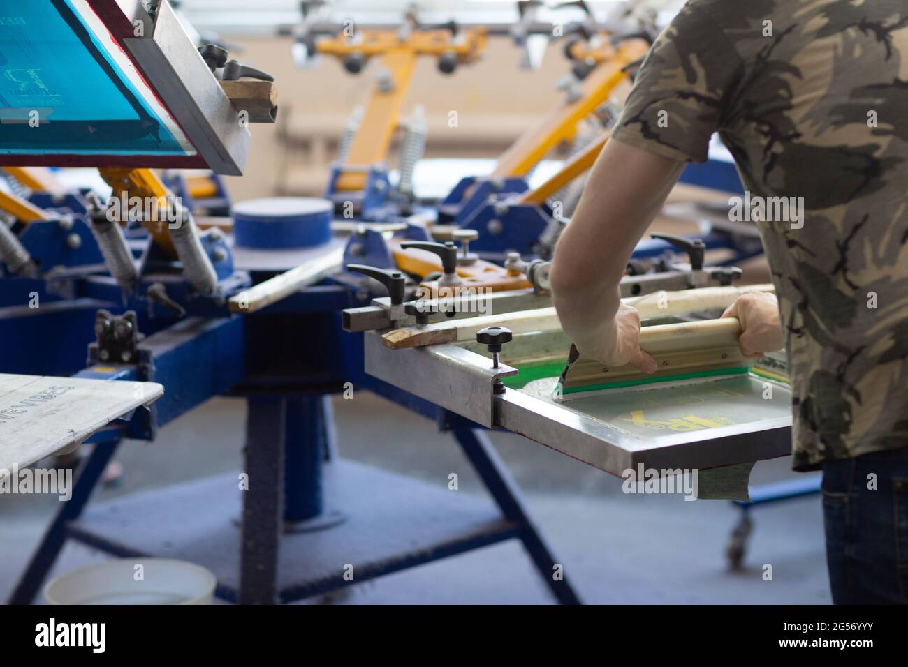 Arbeiter und Siebdruck Siebdruck Siebdruck-Prozess in der Bekleidungsfabrik. Stockfoto