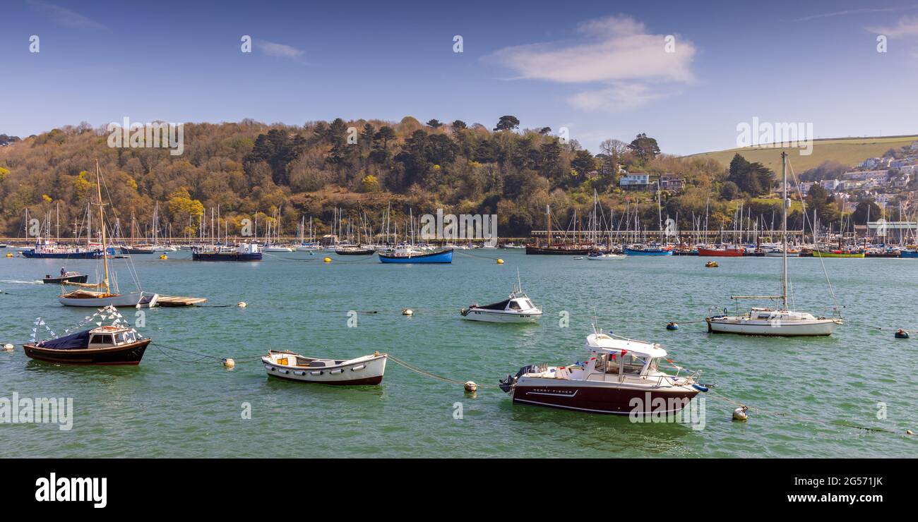 Die Boote vertäuten auf dem Fluss Dart in Dartmouth in Devon. In der Ferne liegt die Dampflokomotive 75014 Braveheart, die in Kingswear ankommt. Stockfoto