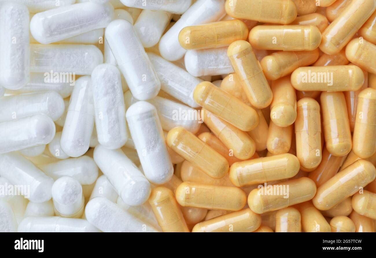 Viele weiße und gelbe Pillen-Kapseln als Hintergrund, Draufsicht. Gesundheitskonzept. Stockfoto