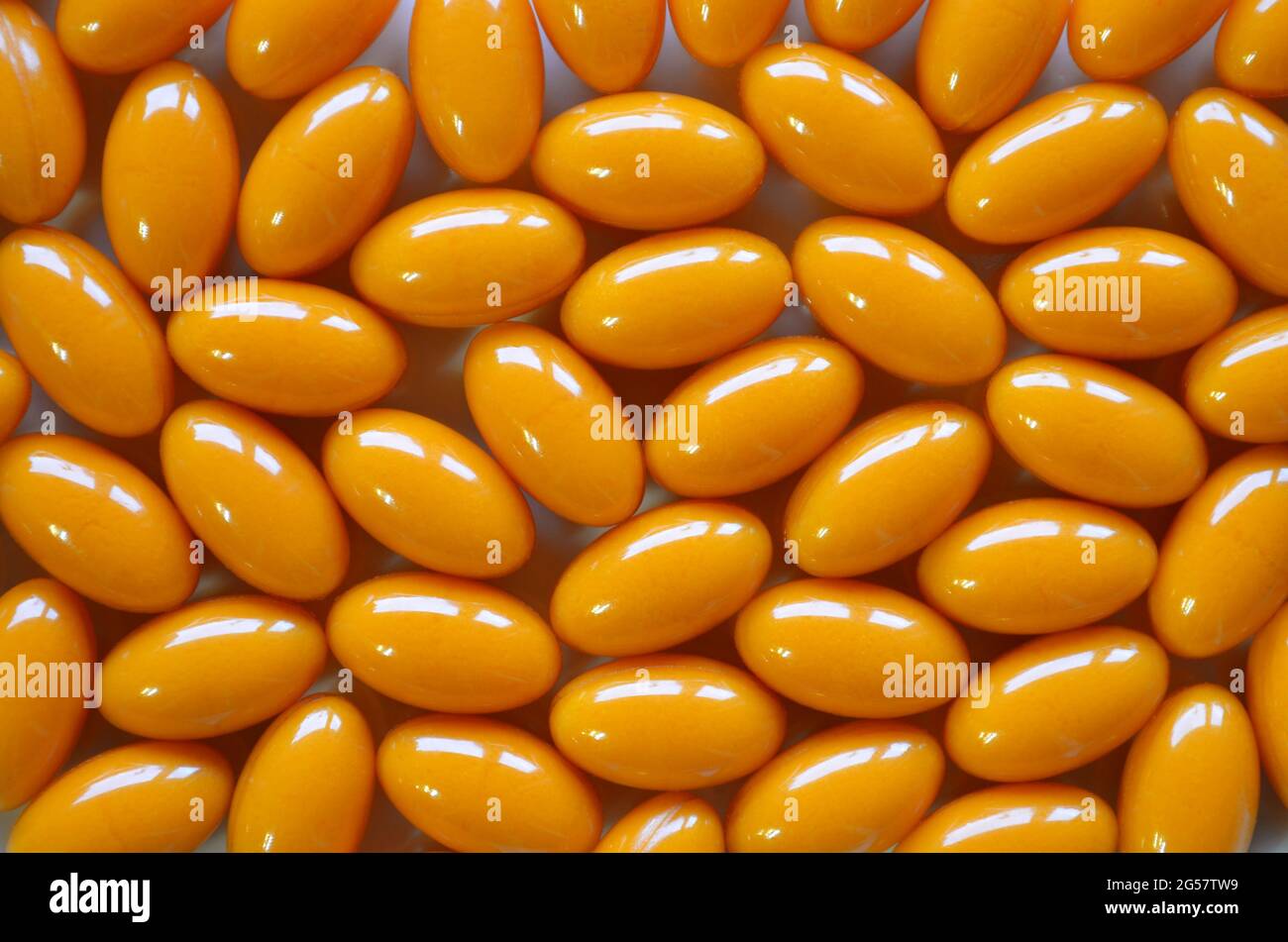 Coenzym Q10 Nahrungsergänzungsmittel in orangen Kapseln als Textur im Vollformat. Vitamine für Gesundheit und Langlebigkeit. Stockfoto