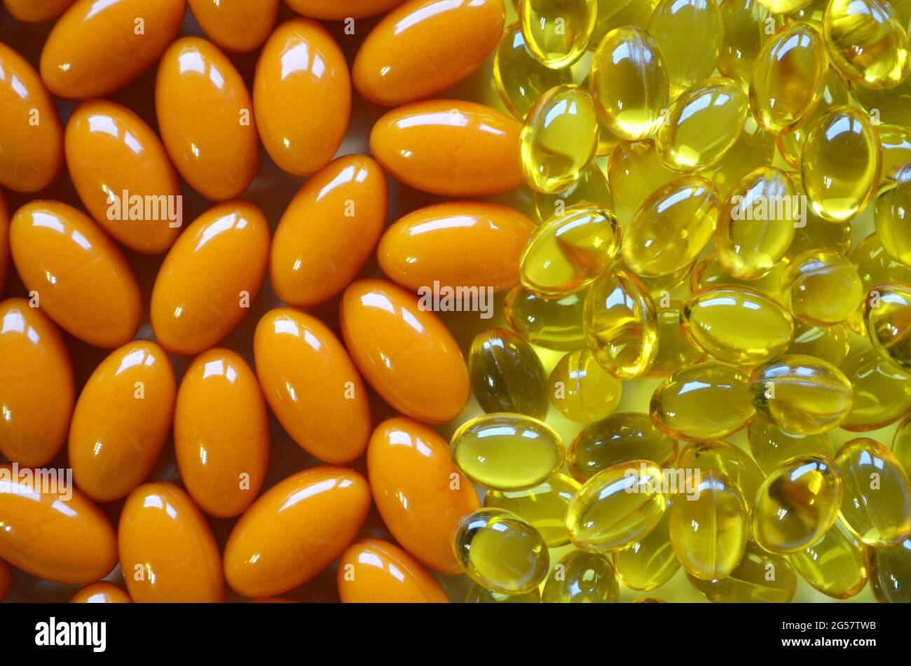 Zwei Arten von Nahrungsergänzungsmitteln in gelben und orangen Kapseln als Textur im Vollformat. Konzept der Pharmaindustrie. Stockfoto