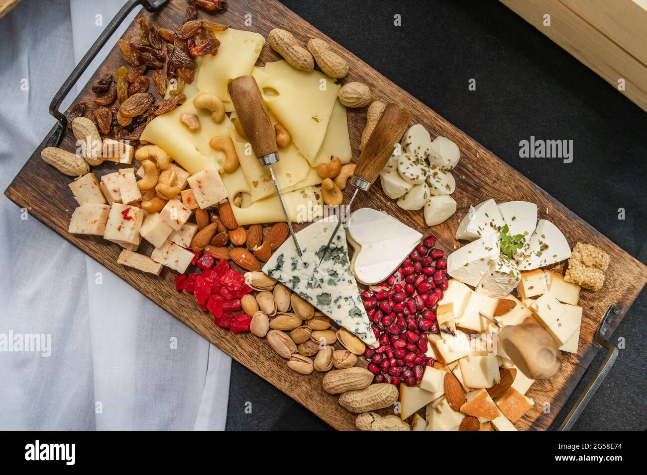 Blick von oben auf Holzbrett auf dem Tisch mit Speisen serviert verschiedenen Geschmack von Käse Rosinen und Trockenobst Stockfoto