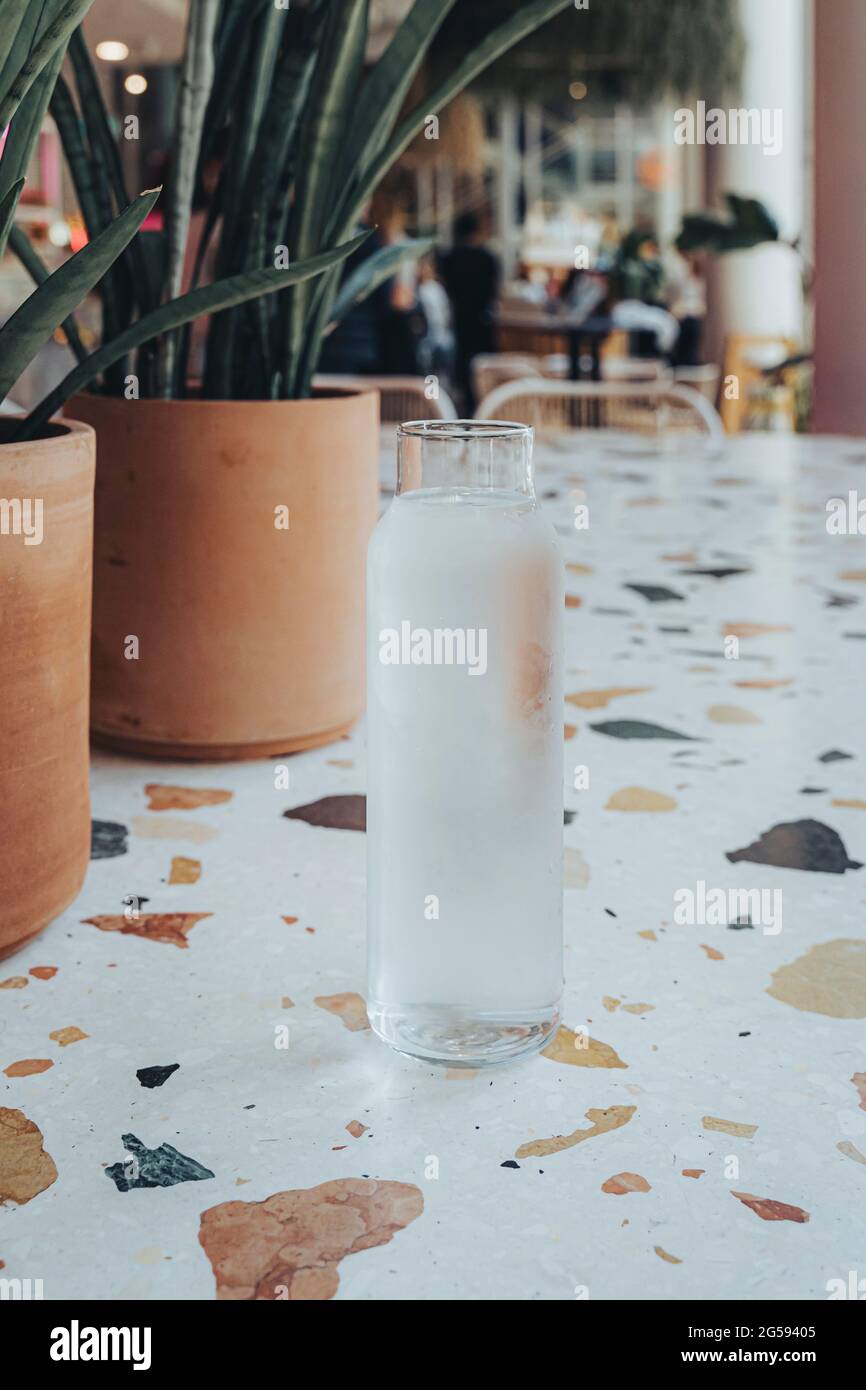 Krug mit Wasser auf einem Marmortisch in einem trendigen Café mit Pflanzen. Stockfoto
