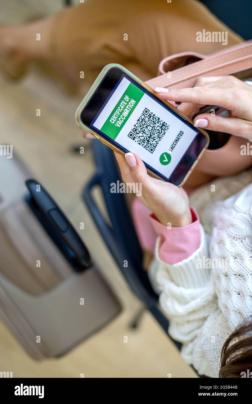 Draufsicht Frau mit Ausweispapieren Impfpass auf Smartphone-Bildschirm am Flughafen Stockfoto
