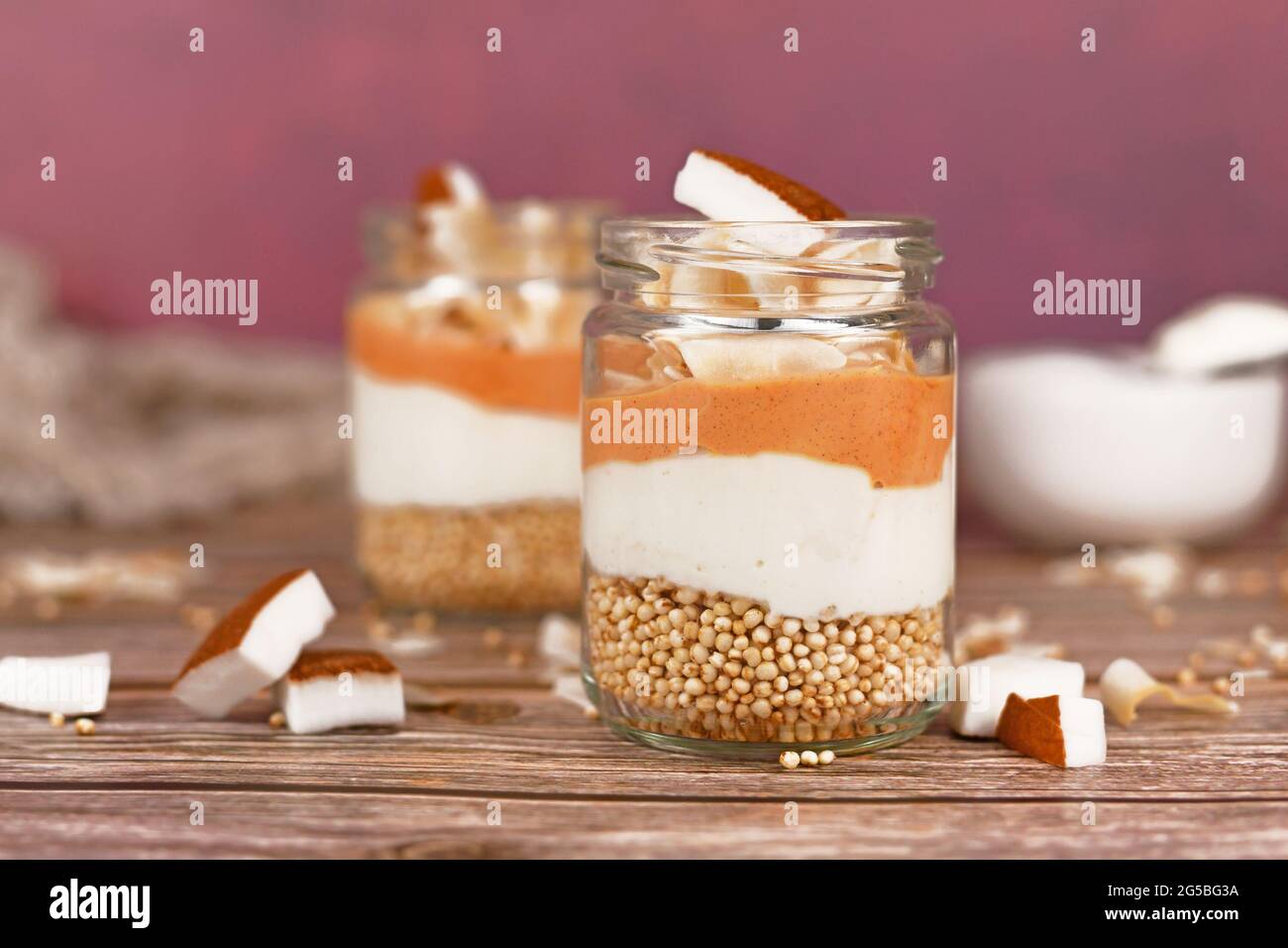 Frühstück oder Dessert in mehreren Schichten mit gepufften Quinoa-Körnern, Joghurt und Kokosflocken und Glasstücken Stockfoto
