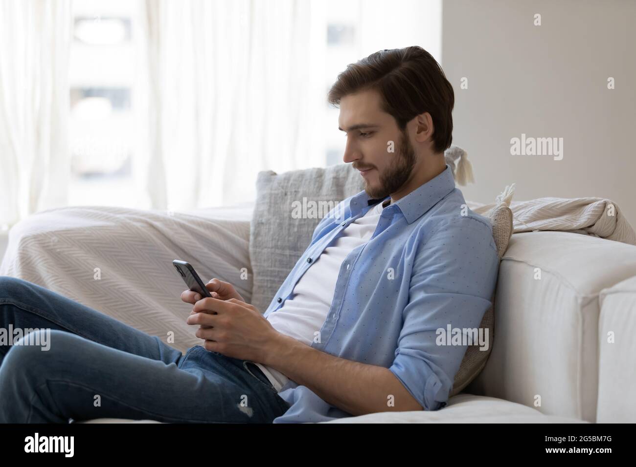 Fokussierter engagierter junger Mann mit Mobiltelefon Stockfoto