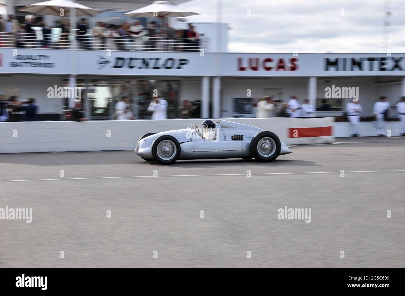 Auto Union Typ D Classic Grand Prix Rennwagen beim Goodwood Revival 2012, UK, mit Geschwindigkeit, vorbei an der Boxenwand und den Crews. VIPs oben Stockfoto