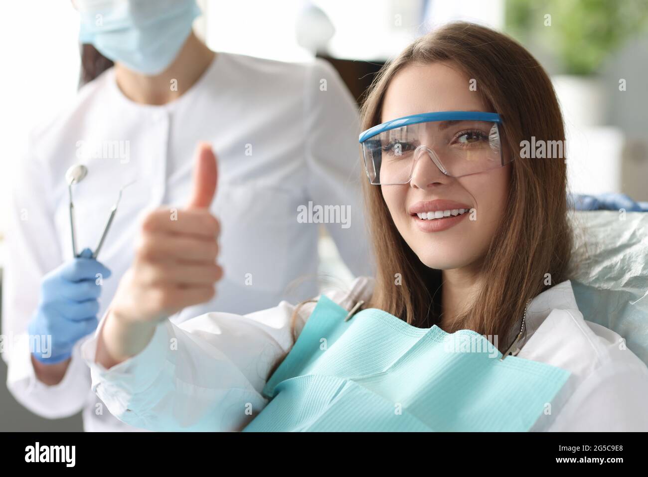 Porträt einer Frau mit einem schönen Lächeln auf den Zahnarzt zeigt Daumen nach oben Geste Stockfoto