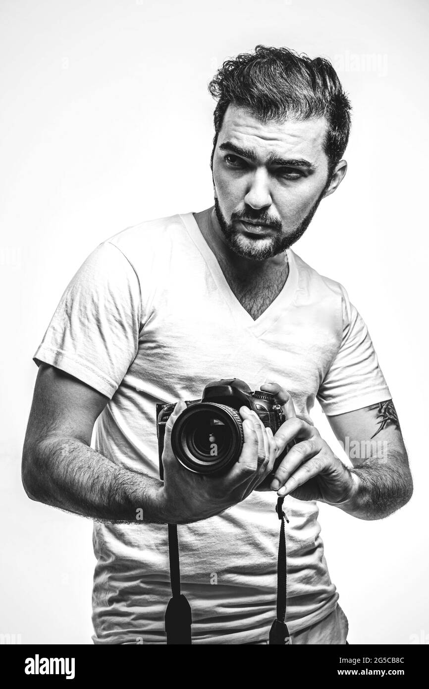 Mann mit Kamera. Harismatiker fotografiert im Studio. Professioneller Fotograf. Hobby. Schwarzweiß-Foto Stockfoto