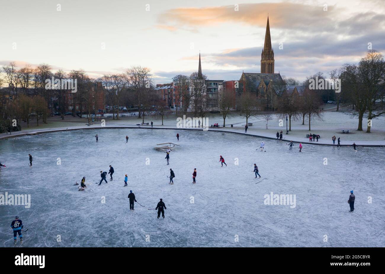 Eishockeyspieler und einige Eiskunstläufer laufen im Winter im Queens Park, Glasgow, Schottland, Großbritannien, auf einem gefrorenen Teich Stockfoto