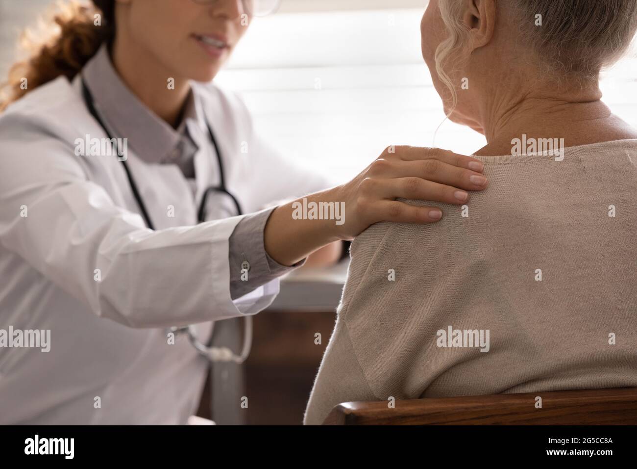 Unterstützende Ärztin tröstet alte Klientin Stockfoto