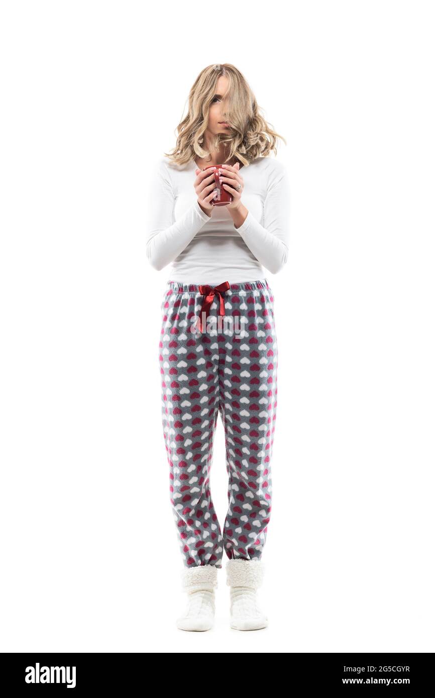 Gerade aufgewacht Frau in Schlafanzug mit durcheinander zerzausten Haaren halten Tasse Kaffee. Ganzkörperlänge isoliert auf weißem Hintergrund. Stockfoto