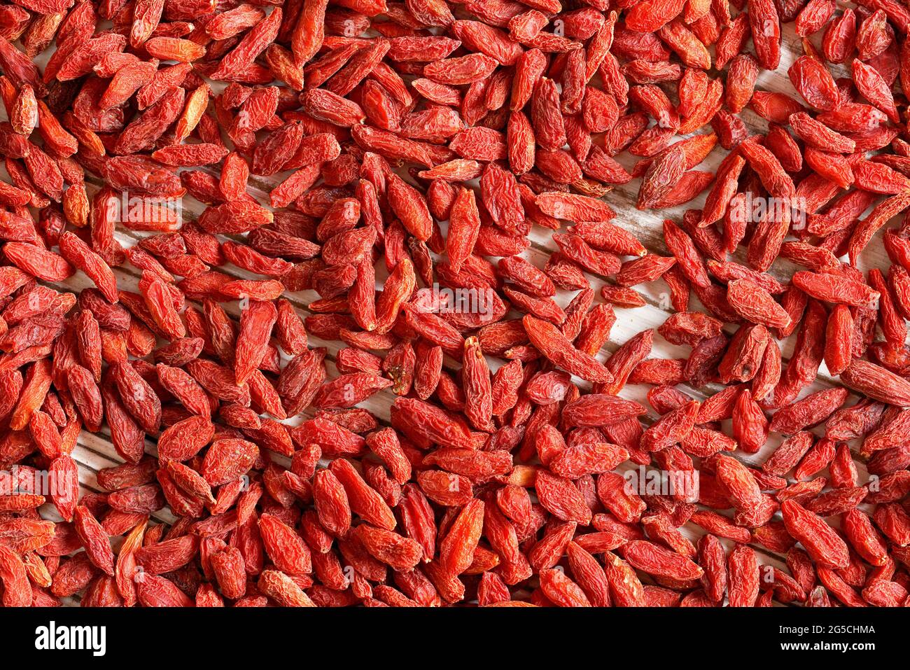 Detail Nahaufnahme von Goji-Beere (Wolfbeere - Lycium chinense) getrockneten Früchten Haufen von oben geschossen, weiß umwoben Brett sichtbar unter Stockfoto
