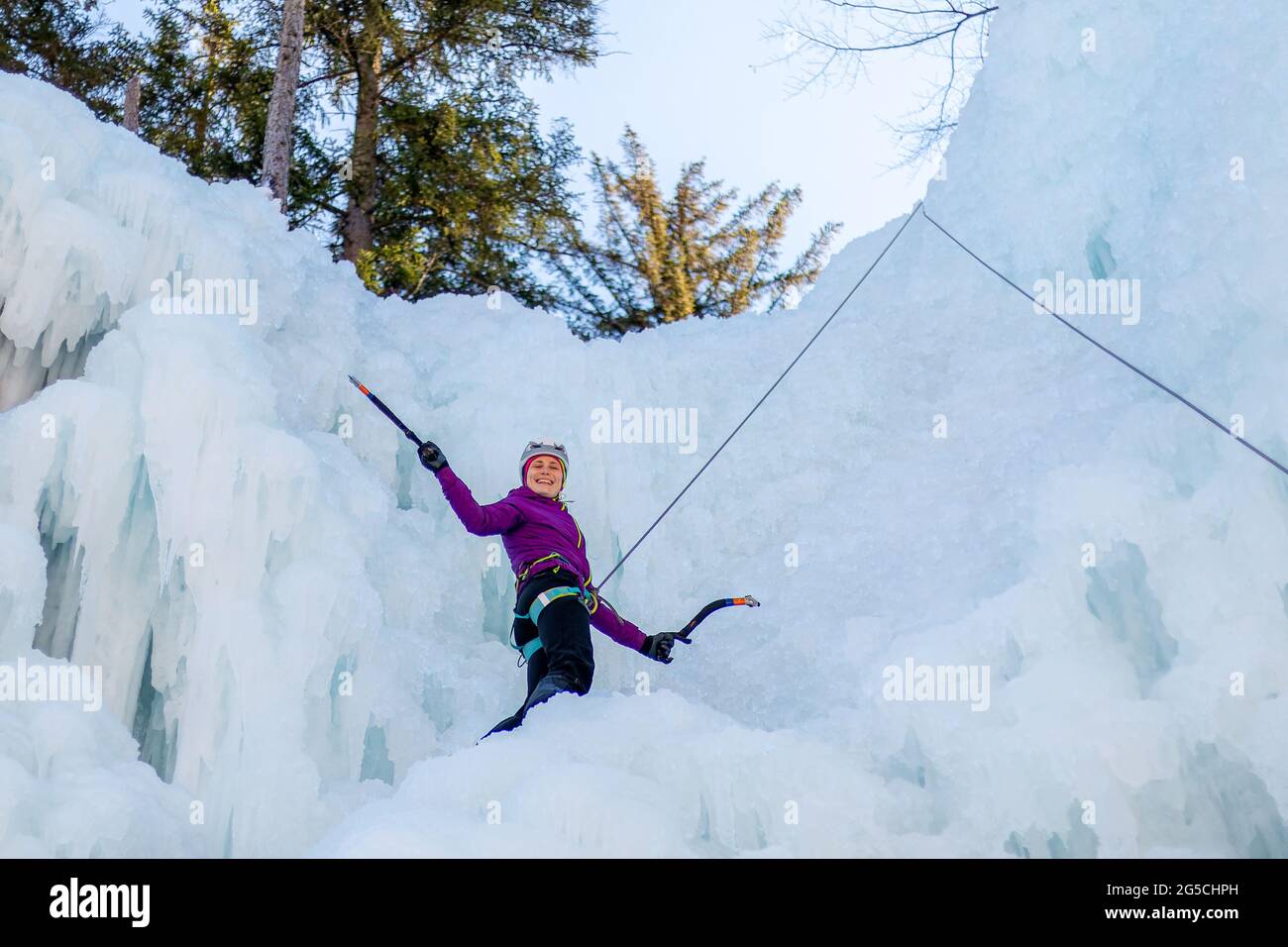Weibliche Eiskletterin Silhouette schwingende Äxte mit Kraft ins Eis, das zerschmetterte Eis fällt Stockfoto