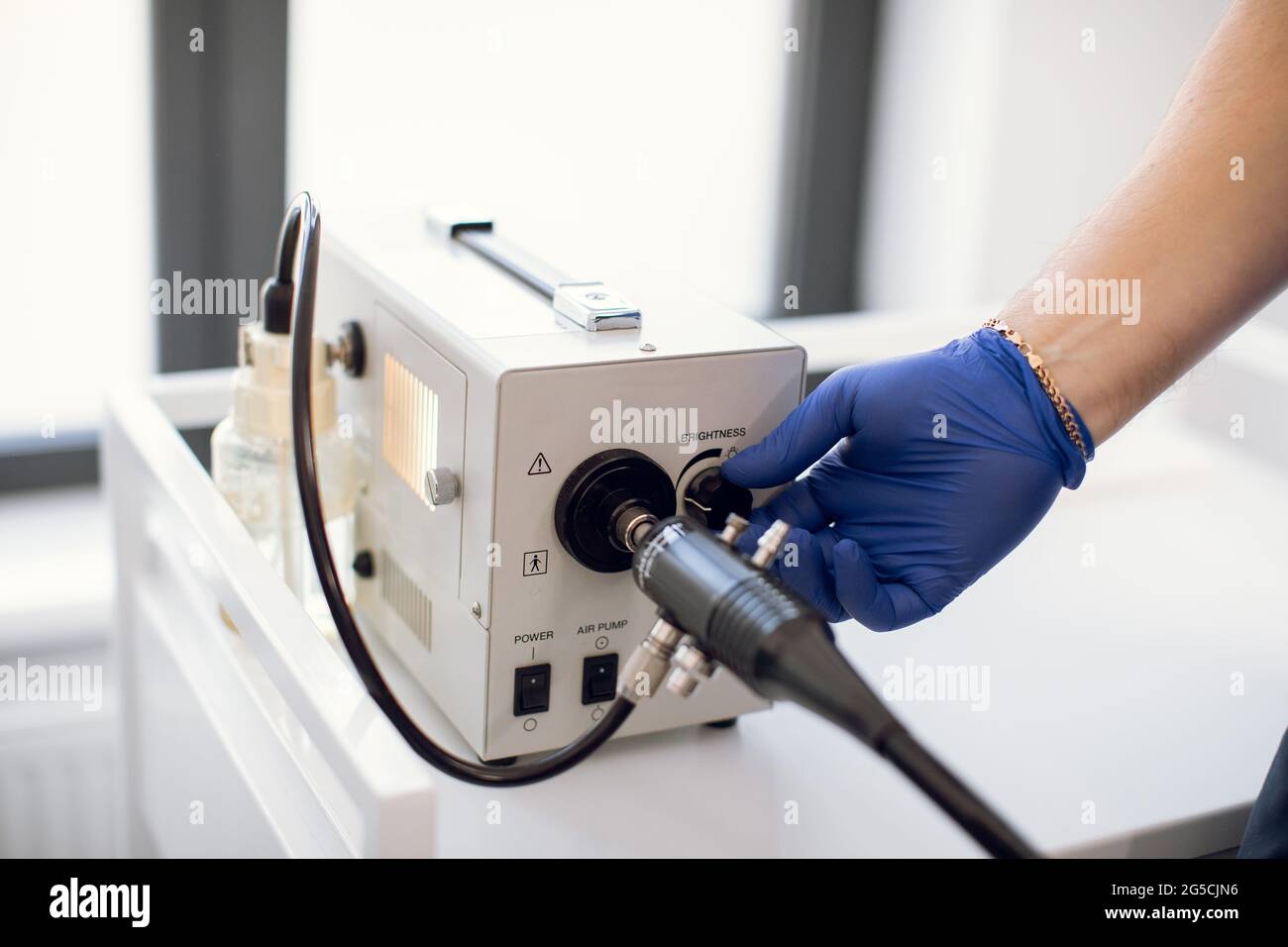 Endoskopie im Krankenhaus. Nahaufnahme eines modernen gastroduodenoskopischen Geräts und der Hand eines nicht erkennbaren Arztes in einem sterilen blauen Gummihandschuh, der sich auf das Endoskopieverfahren vorbereitet Stockfoto