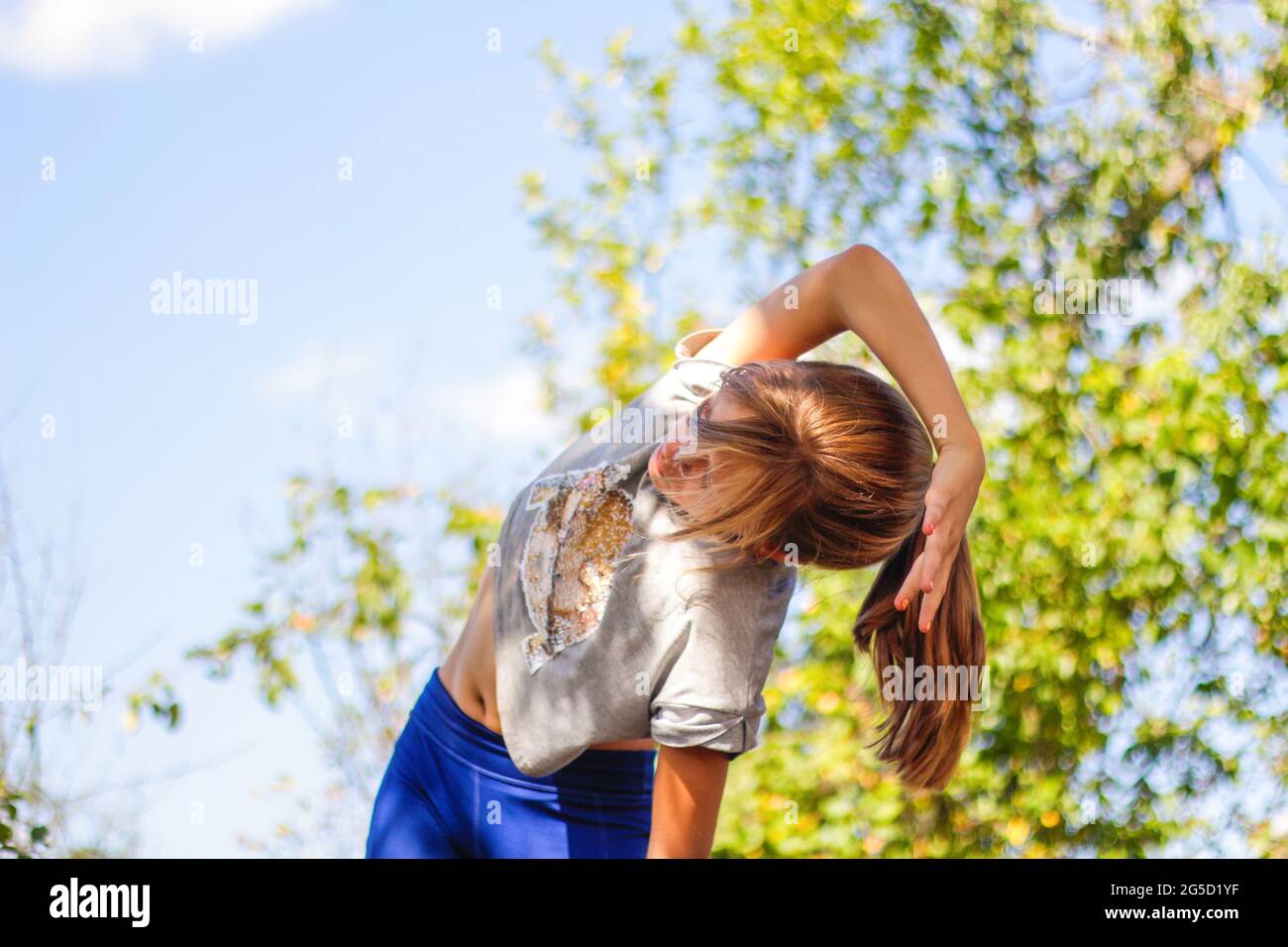 Defocus caucasian preteen Mädchen tun körperliche Bewegung im Park, Wald, im Freien, draußen. Meditation, Konzentration. Gesunder Lebensstil. Seitenbiegung Stockfoto