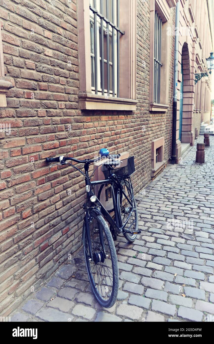 Blick auf eine Seitenstraße in der historischen Altstadt von Düsseldorf, Deutschland, mit Retro-Fahrrad, Backsteingebäude und Pflastersteinpflaster. Stockfoto