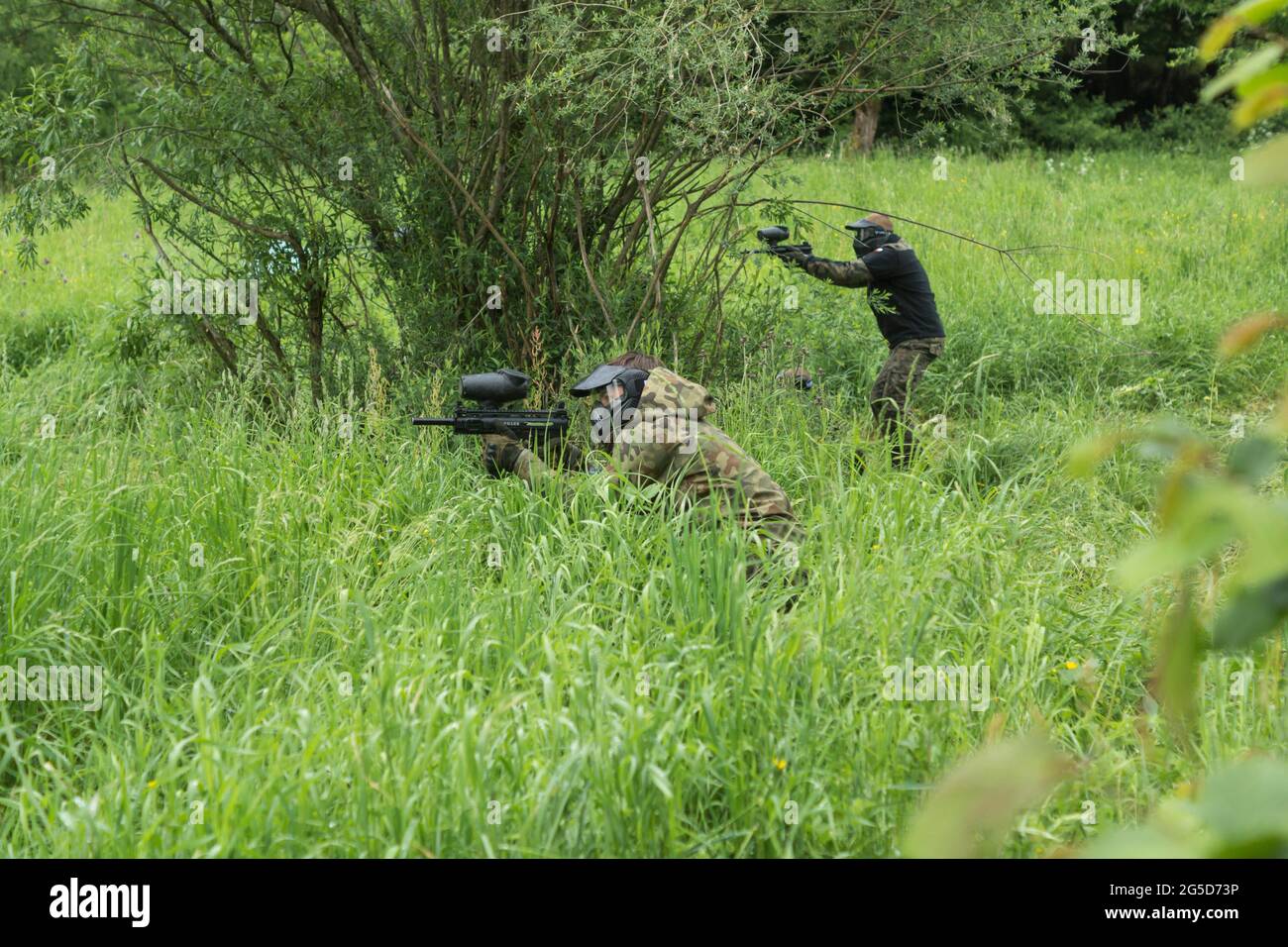 Gruppe maskierter Menschen, die im Wald Paintball spielen Stockfoto