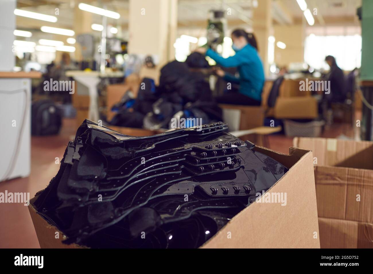 Stapel von schwarzen Lederdetails für zukünftige Stiefel in Karton in der Schuhfabrik Stockfoto