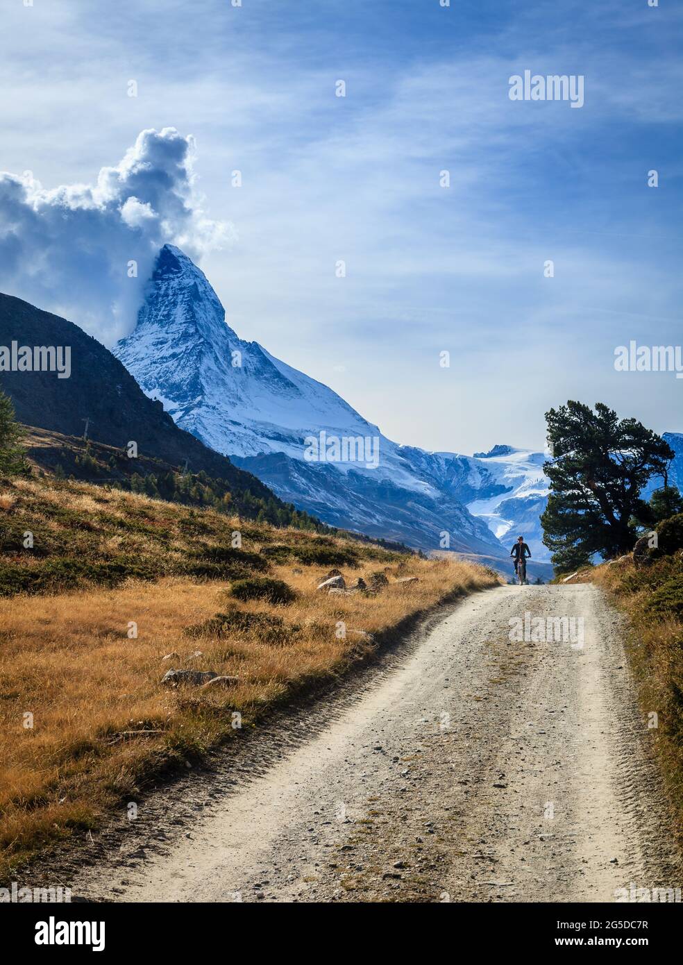 Ein Radfahrer auf einer Schotterstraße in den Schweizer Alpen mit Matterhorn im Hintergrund Stockfoto