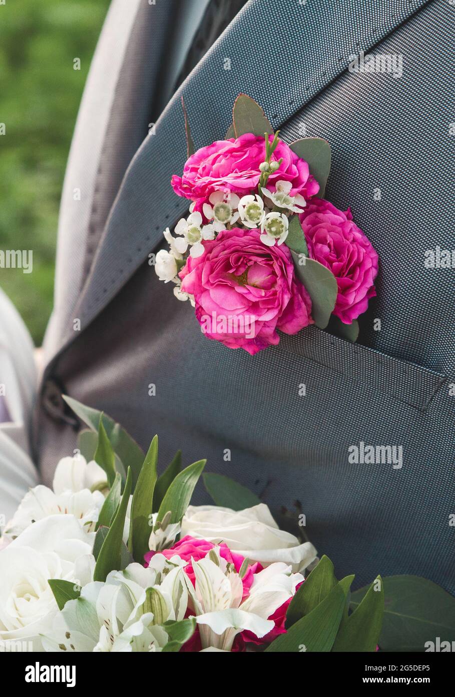 Rosafarbene Boutonniere auf dem grauen Anzug des Bräutigams, Nahaufnahme, Hochzeitselement der Einrichtung des Mannes. Stockfoto