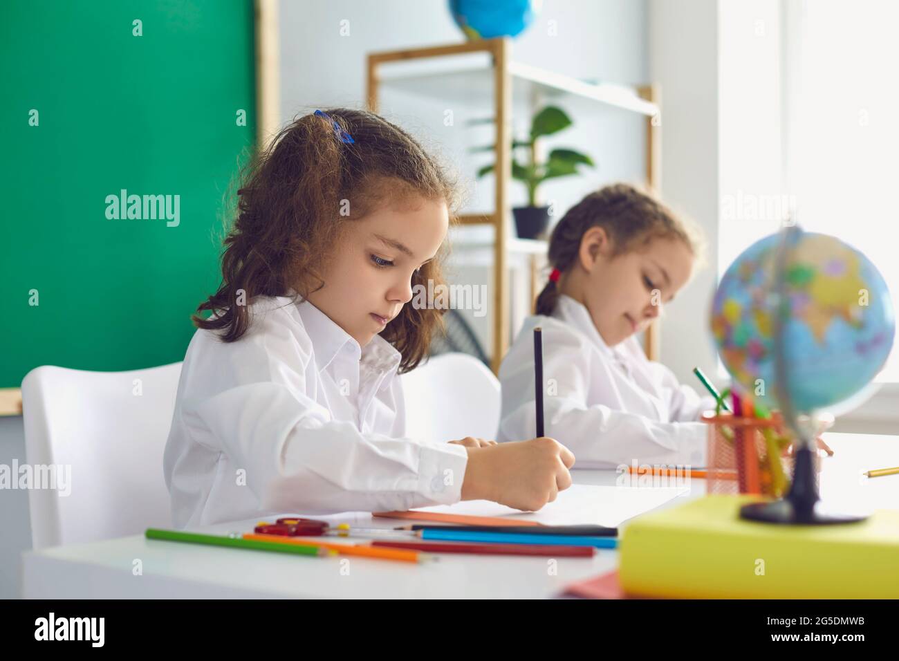 Zurück zur Schule. Kinder Schüler schreiben, während sie am Tisch im Klassenzimmer sitzen. Stockfoto