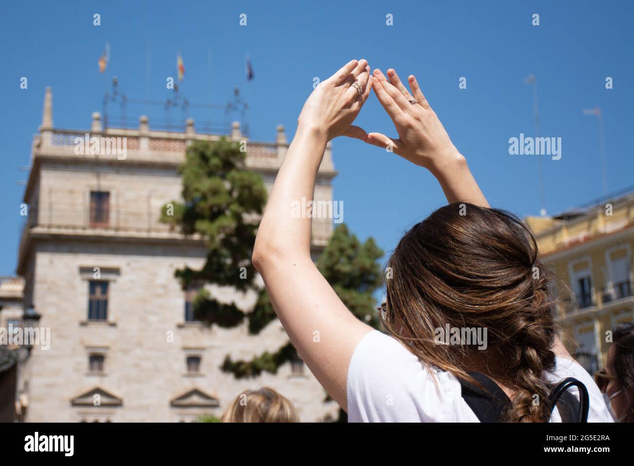 Valencia Spanien. 26. Juni 2021 – EINE Frau macht während einer Demonstration zur Verteidigung der Frauenrechte mit ihren Händen ein feministisches Symbol. Im Hintergrund Th Stockfoto