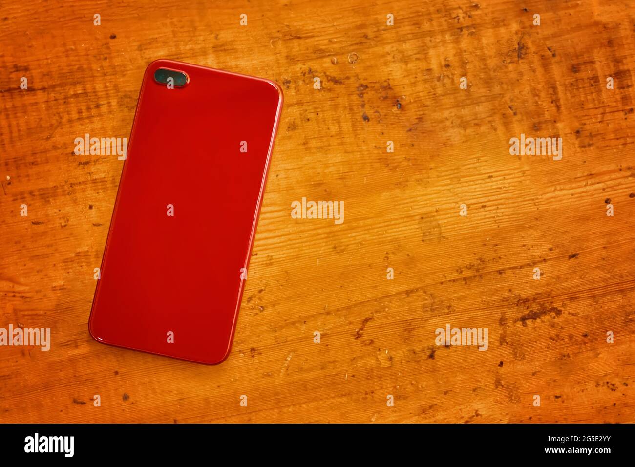 Rotes Handy auf Holztisch. Modernes Gadget für Leben und Geschäft. Draufsicht auf persönliches Zubehör. Flach liegend mit Kopierplatz. Stockfoto