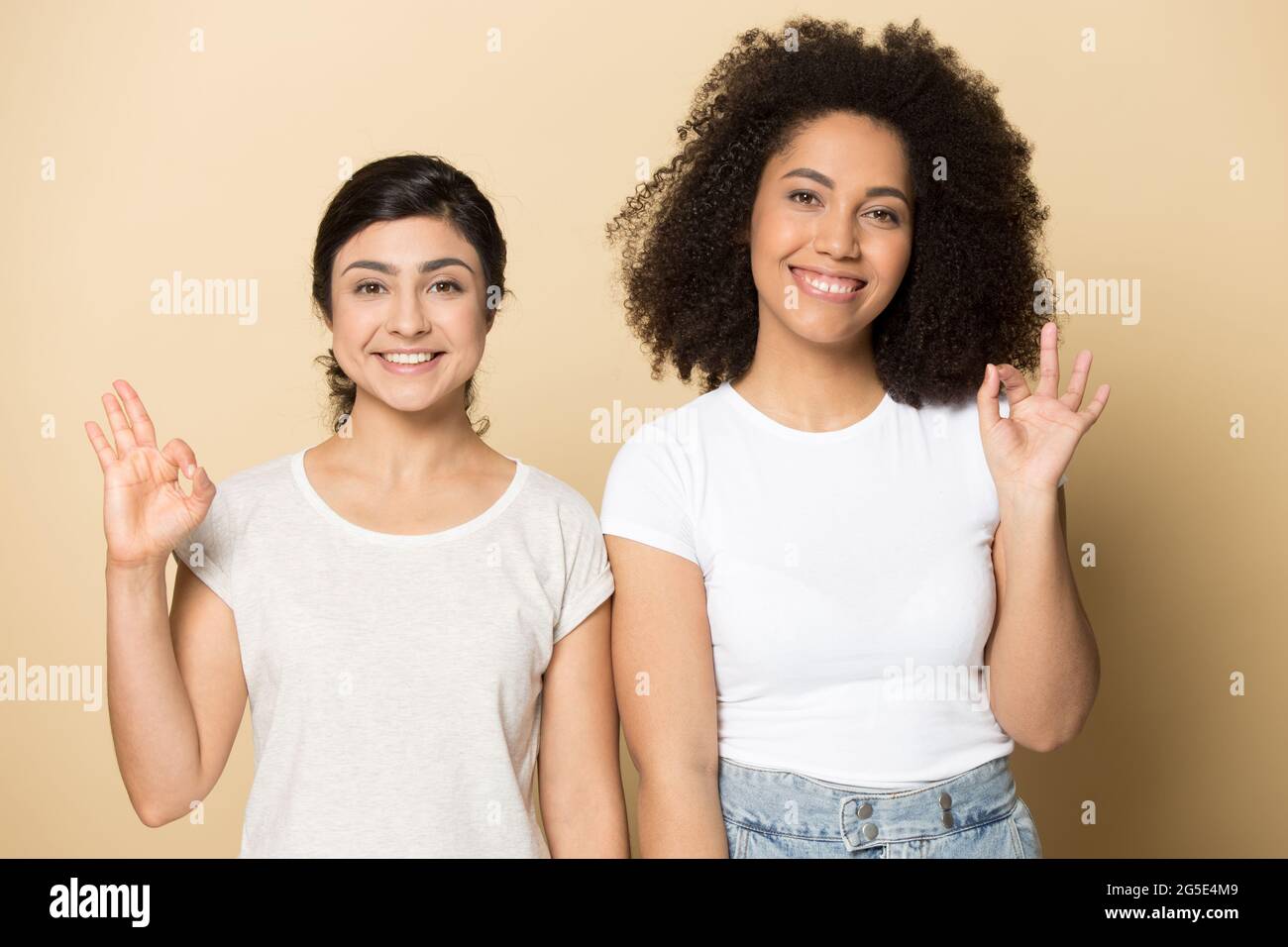 Porträt von lächelnden verschiedenen Freundinnen zeigen ok Zeichen Stockfoto