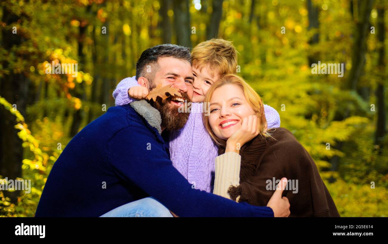 Eltern und Kind gemeinsam im Park am sonnigen Herbsttag. Glückliche Familie, Mutter und Vater umarmen den kleinen Sohn. Glückliches Paar mit Kind im Freien. Stockfoto