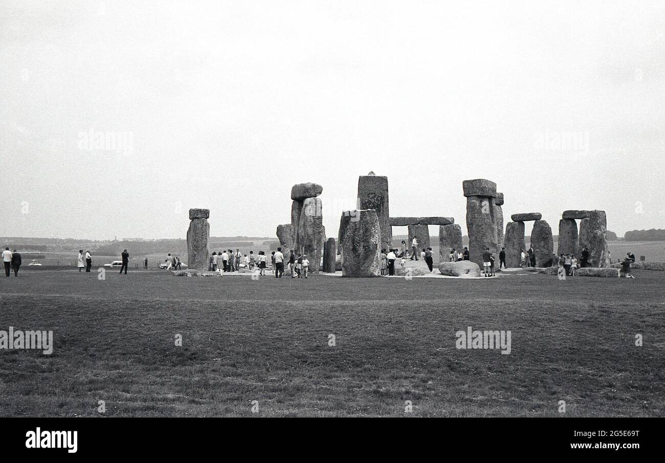 1960er, historisch, Außenansicht der Besucher bei den alten Steinen in Stonehenge, Wiltshire, England, Großbritannien. Zu dieser Zeit konnte man frei um die prähistorischen Steine herumlaufen, aber in den folgenden zehn Jahren wurden die Steine aufgrund der Besucherzahlen, der Beschädigung des Grases und der Erosion an der heiligen, antiken Grabstätte abgespalten, um den Zugang zu verhindern. Cecil Chubb, der sich auf dem Anwesen der Abtei von Amesbury befindet und sich zu einer Zeit im Besitz von König Heinrich VIII. War, brachte das Grundstück mit den Steinen auf einer Auktion im Jahr 1915 und gab es 1918 an die britische Nation. Stockfoto