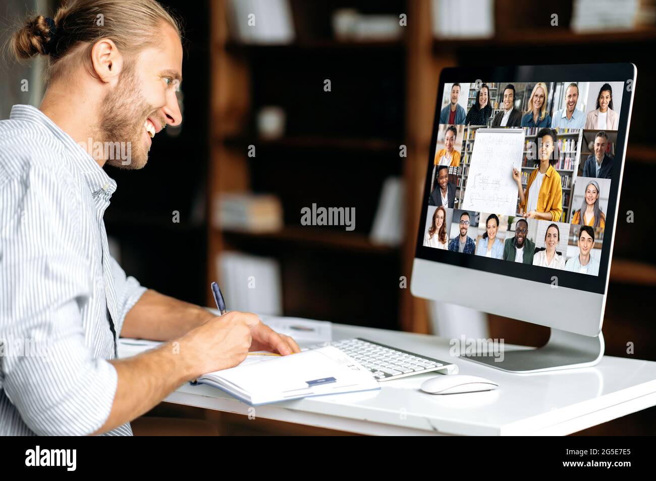 Online-Schulungen. Smart kaukasischen Kerl gewinnt Wissen beobachten Lektion online. Der junge Mann notiert sich während des Webinars und hört den Vortrag über einen Videoanruf. Lehrerin und Schüler auf einem Bildschirm Stockfoto
